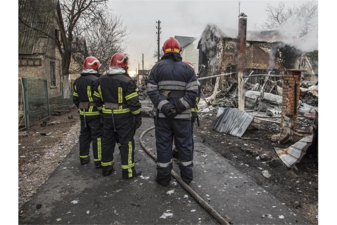 Feuerwehrleute betrachten die Trümmer eines Flugzeugs das zwischen Häusern abgestürzt ist. Es war unklar, wessen Flugzeug abgestürzt ist und wer es zum Absturz gebracht hat. Russische Truppen sollen bis in die Außenbezirke der Hauptstadt vorgedrungen sein. Foto: Oleksandr Ratushniak/AP/dpa