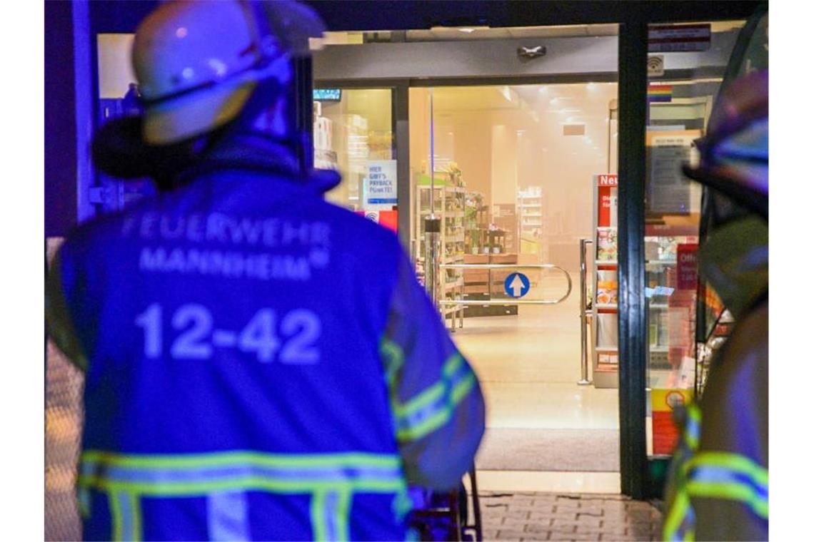 Brand in Mannheimer Supermarkt: Sechs Leichtverletzte Feuerwehrleute blicken in den verqualmten Eingangsbereich eines Supermarktes. Foto: Rene Priebe/pr-video/dpa