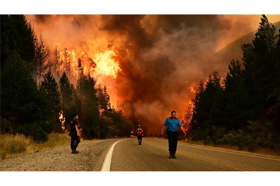 Feuerwehrleute gehen auf einer Straße während eines Waldbrandes in Argentinien.