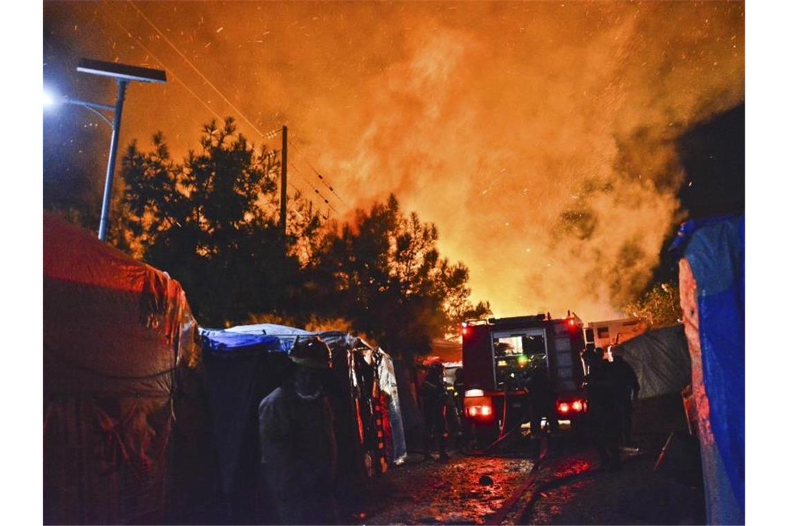 Feuerwehrleute kämpfen gegen den Brand in dem überfüllten Migrantenlager. Foto: Michael Svarnias/AP/dpa