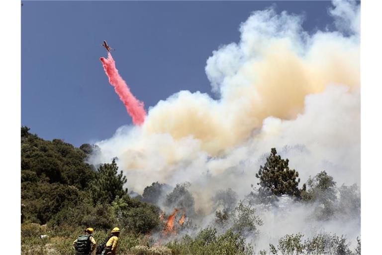 Feuerwehrleute kämpfen mit Unterstützung von Löschflugzeugen gegen den Waldbrand im Bezirk Riverside County. Foto: -/XinHua/dpa