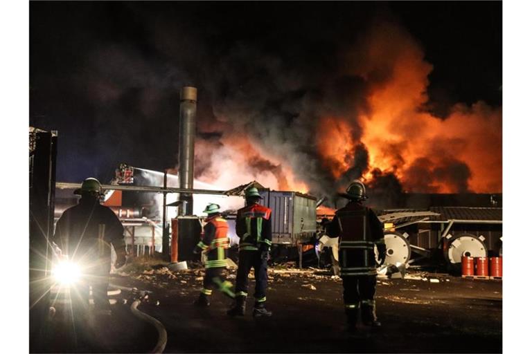 Feuerwehrleute löschen den Brand in einer Tapetenfabrik. Foto: Nadine Weigel/dpa