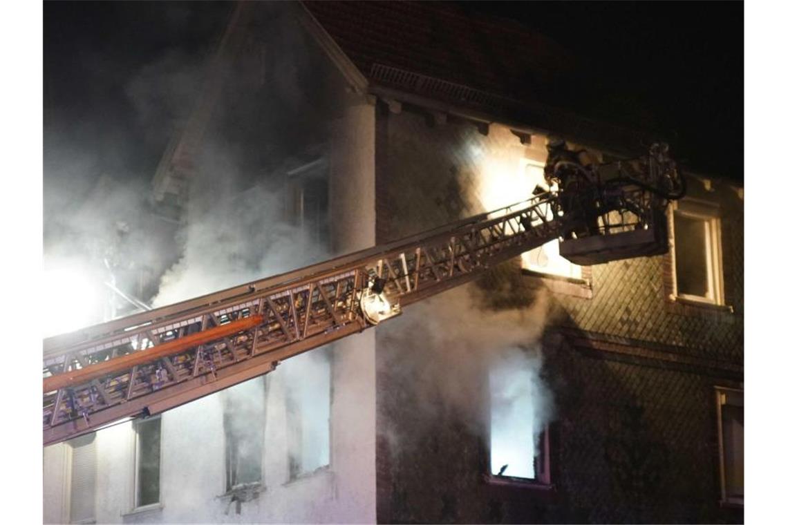 Feuerwehrleute löschen einen Brand in einem Wohnheim für Flüchtlinge und Obdachlose. Foto: Kohls/SDMG/dpa