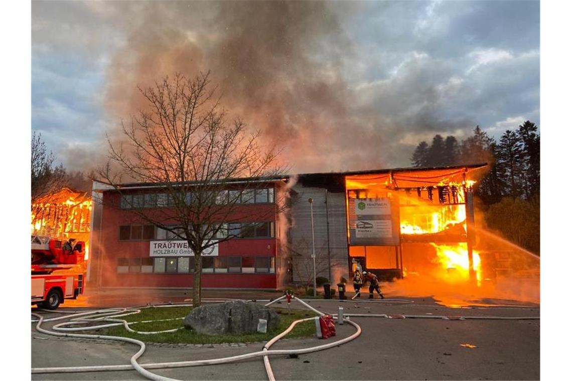 Feuerwehrleute löschen einen Firmenkomplex in Achberg, der in voller Ausdehnung brennt. Foto: Benjamin Liss/dpa
