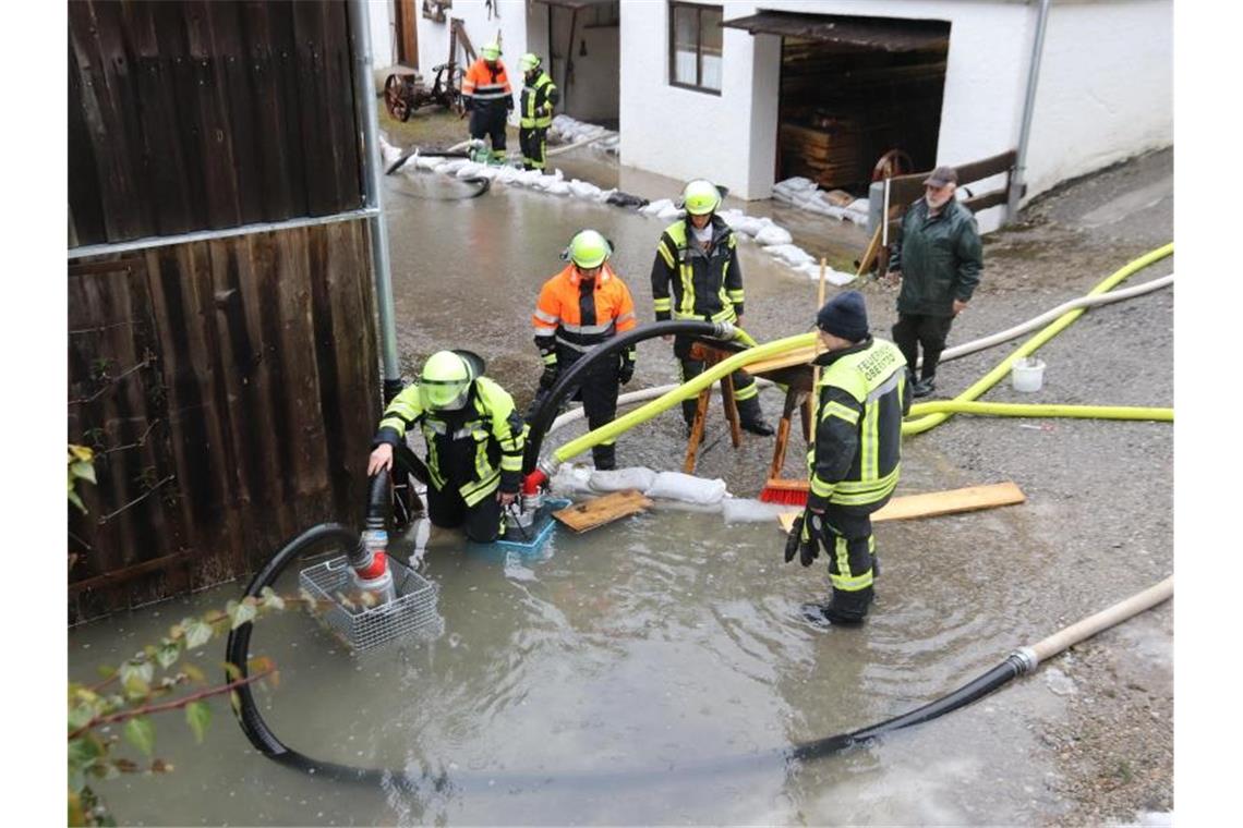 Feuerwehrleute pumpen an einem Haus bei Oberstdorf Wasser ab. Foto: Benjamin Liss/dpa