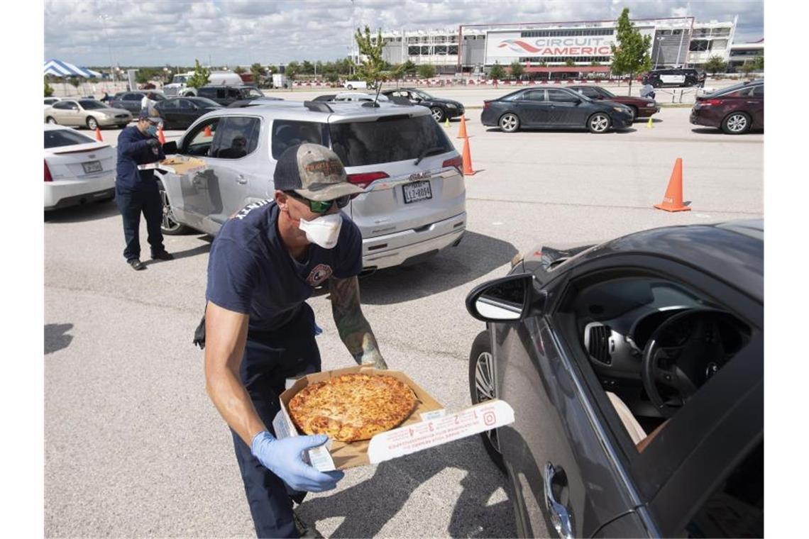 Feuerwehrleute reichen Autofahrern während der Evakuierung in Austin, Texas, Pizza. Foto: Bob Daemmrich/ZUMA Wire/dpa