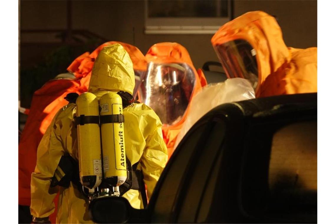 Feuerwehrleute sind in Schutzanzügen im Einsatz. Foto: Matthias Strauß/dpa