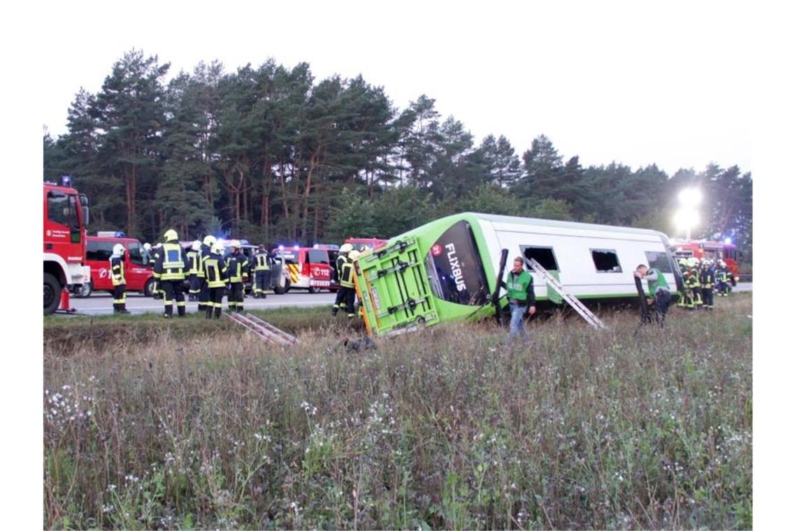 Feuerwehrleute stehen an der Autobahn A24 neben einem verunglückten Fernbus. Bei dem Fernbusunglück hat es am frühen Morgen nach Polizeiangaben 31 Verletzte gegeben. Foto: Ralf Drefin/dpa