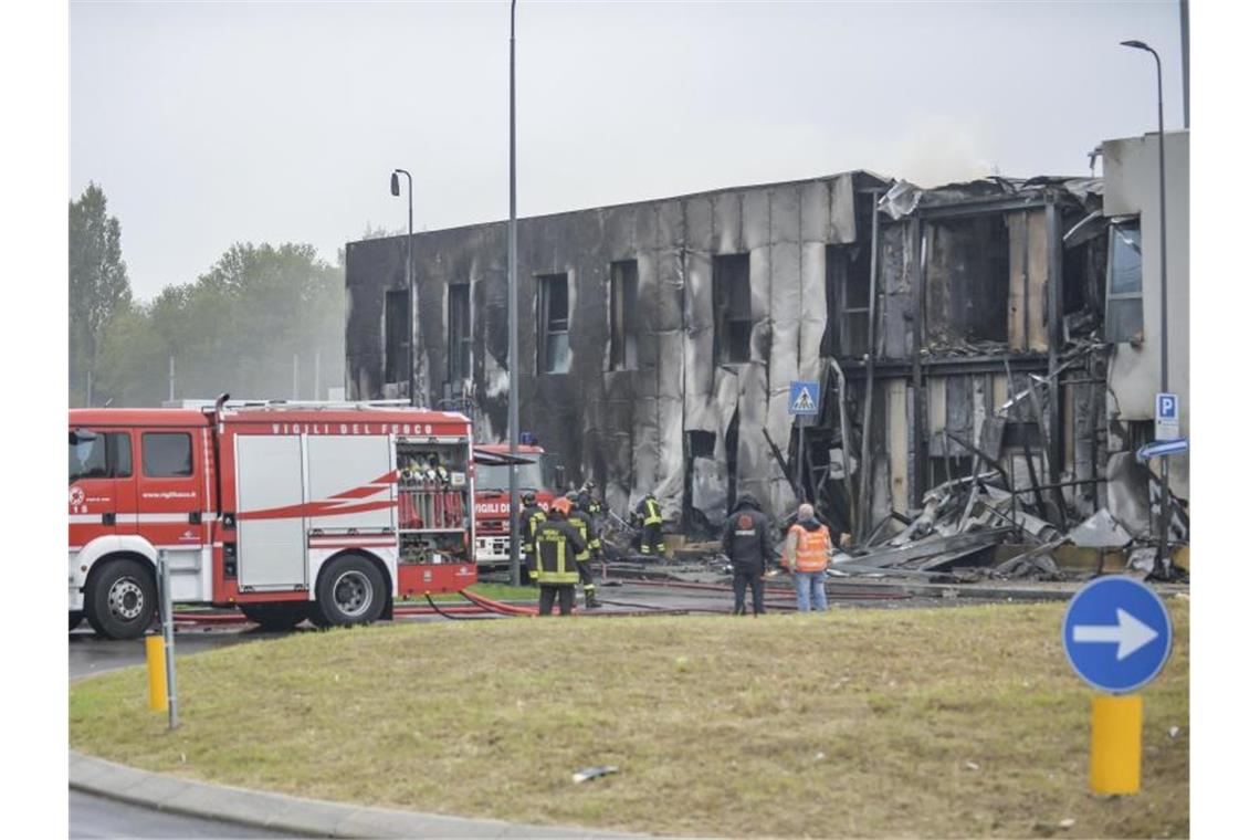 Feuerwehrleute stehen an der Unfallstelle, nachdem ein Leichtflugzeug kurz nach dem Start abgestützt und in ein leerstehendes Bürogebäude gekracht ist. Foto: Claudio Furlan/LaPresse/AP/dpa