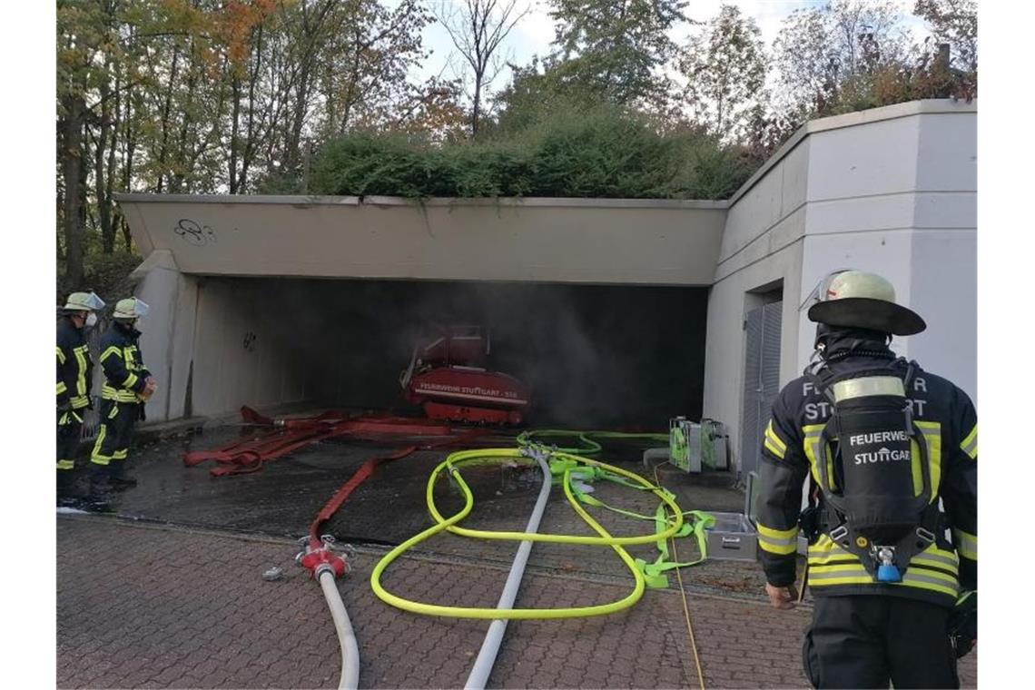 Feuerwehrleute stehen an der Zufahrt einer Tiefgarage, aus der Rauch quillt. Foto: Andreas Rosar/dpa