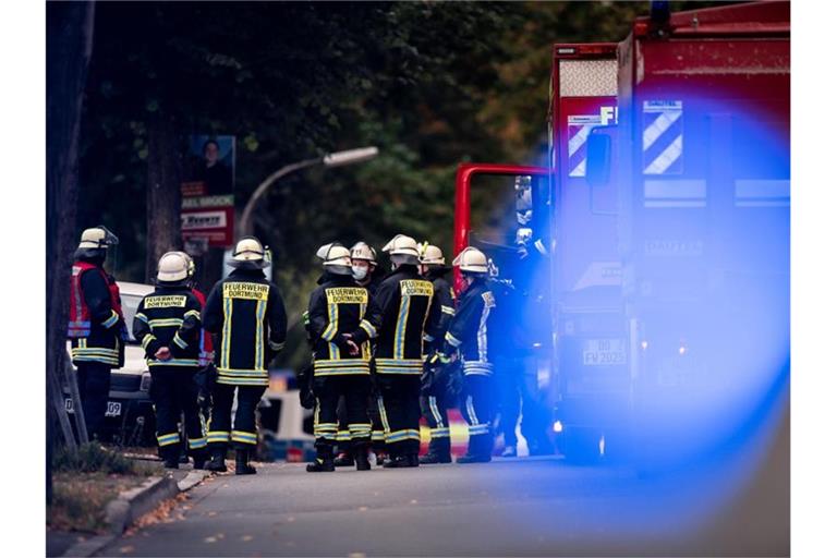Feuerwehrleute stehen auf der gesperrten Volksgartenstraße in Dortmund beim Einsatz im Zusammenhang mit der Wohnungsdurchsuchung. Foto: Fabian Strauch/dpa