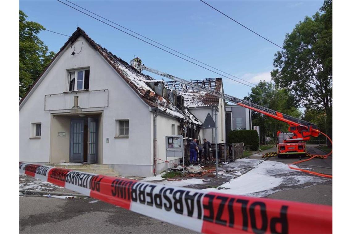 Feuerwehrleute stehen in einem Kran über einem Gebäude, dessen Dach mit Löschschaum bedeckt ist. Foto: Andreas Rosar