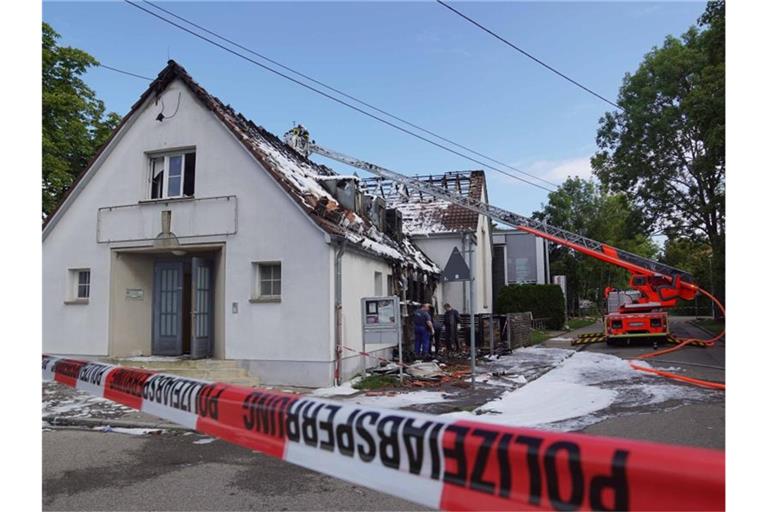Feuerwehrleute stehen in einem Kran über einem Gebäude, dessen Dach mit Löschschaum bedeckt ist. Foto: Andreas Rosar