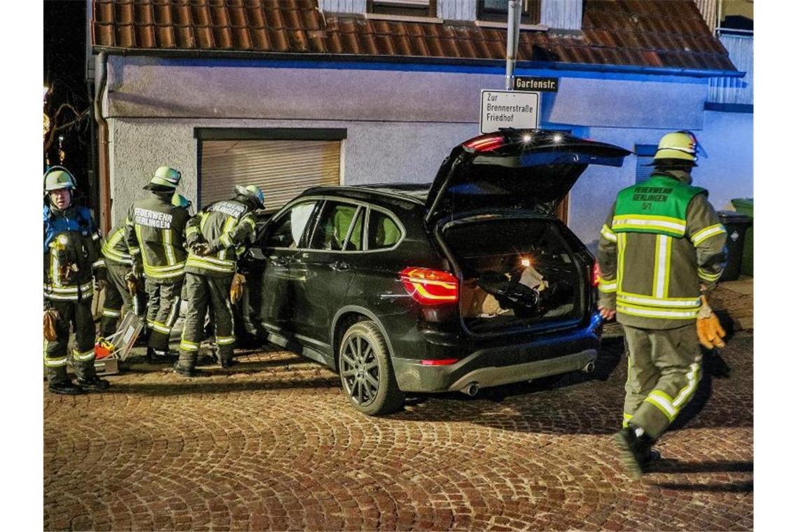 Feuerwehrleute stehen neben einem Auto vor einer stellenweise zertrümmerten Wohnzimmerwand. Foto: Andreas Rometsch/KS-Images.de/dpa
