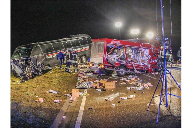 Feuerwehrleute stehen neben einem zerstörten Kleinlaster und einem Reisebus. Foto: Dennis Straub/Ostalp Network/dpa