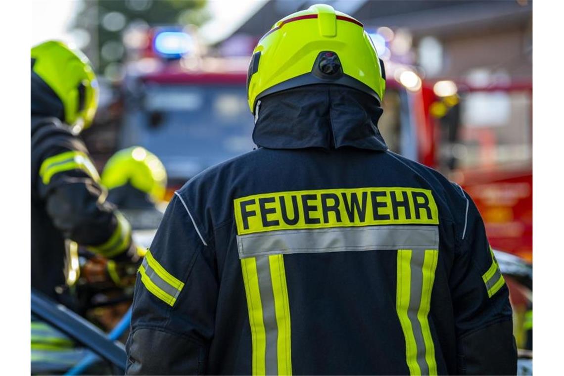 Ein Toter nach Brand in Mannheimer Mehrfamilienhaus Feuerwehrleute stehen um ein Auto, das einen Unfall gehabt hat. Foto: David Inderlied/dpa/Symbolbild