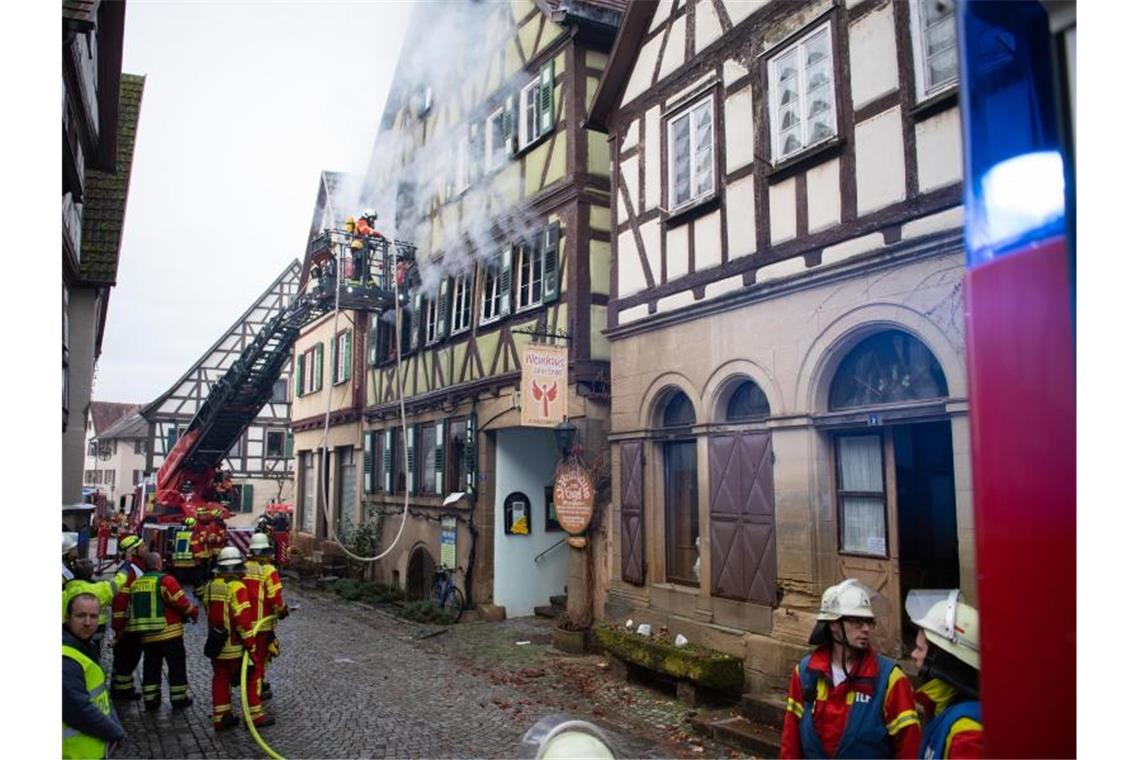 Feuerwehrleute stehen vor dem brennenden Fachwerkhaus in Neudenau. Foto: Tom Weller/dpa