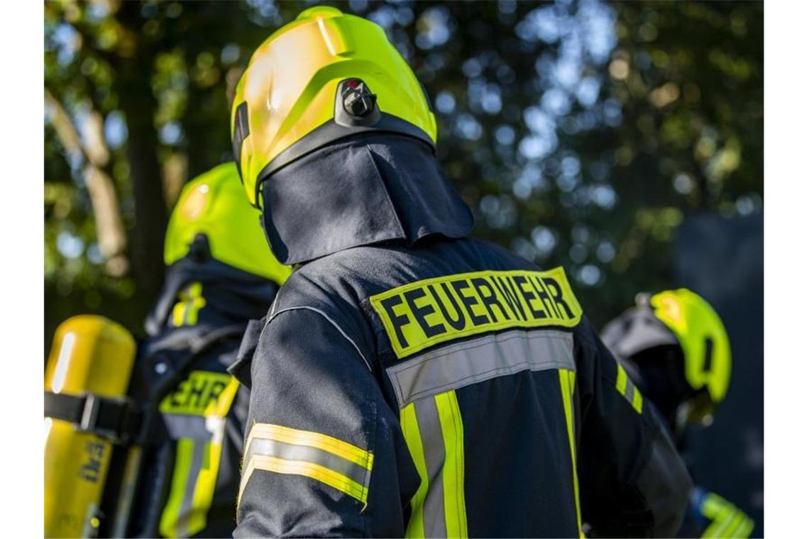 Hoher Schaden nach Brand nahe Ludwigsburg Feuerwehrleute stehen zusammen, um den Einsatz zu besprechen. Foto: David Inderlied/dpa/Symbolbild
