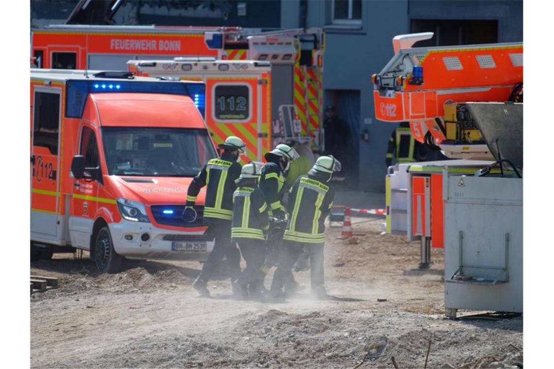 Mühevolle Rettungsaktion: Arbeiter auf Baustelle verschüttet Feuerwehrleute tragen ihre Ausrüstung zur Einsatzstelle auf die Baustelle in Bonn. Foto: Henning Kaiser/dpa
