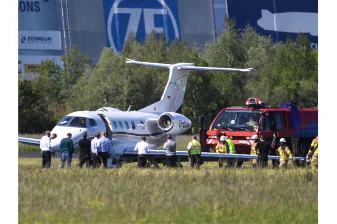 Bodensee-Airport: Notlandung von Privatjet mit acht Insassen Feuerwehrleute und ein Löschfahrzeug stehen neben einem notgelandeten Passagierjet. Foto: Felix Kästle/dpa