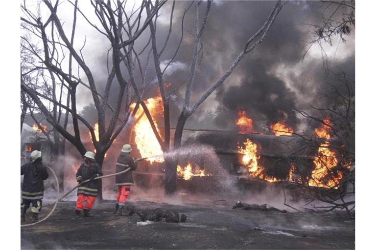 Feuerwehrleute versuchen den Brand des umgestürzten Tanklasters zu löschen. Foto: Stringer/AP/dpa