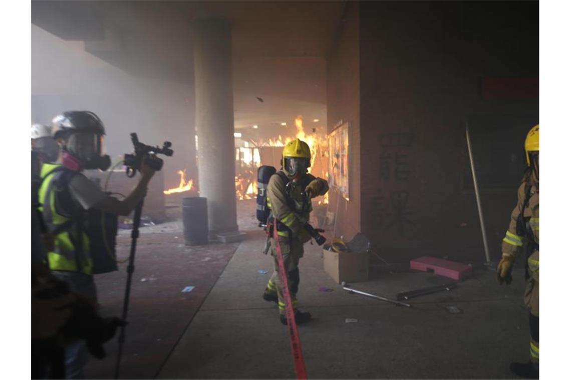 Feuerwehrleute versuchen ein von Demonstranten ausgelöstes Feuer in der Polytechnischen Universität zu löschen. Foto: Dita Alangkara/AP/dpa