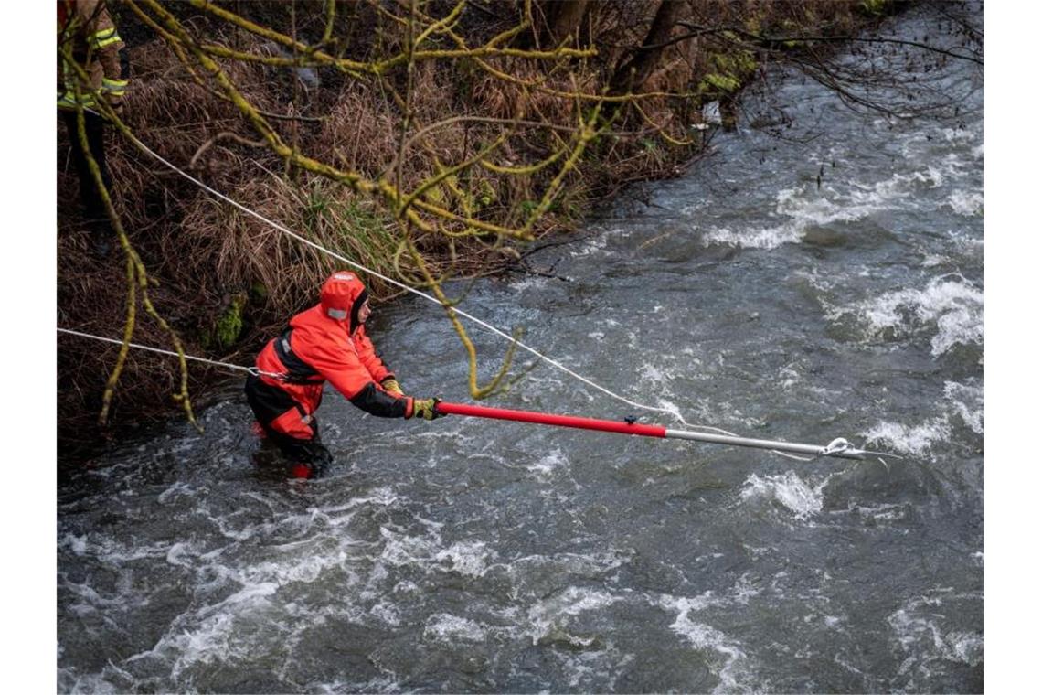 Feuerwehrleute versuchen, einen Gegenstand aus dem Fluss zu bergen. Foto: Fabian Strauch/dpa