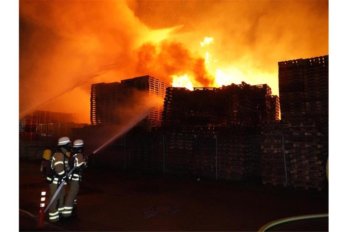 Palettenfirma-Gebäude abgebrannt: 2,5 Millionen Euro Schaden Feuerwehrleute versuchen Stapel von brennenden Holzpaletten zu löschen. Foto: Andreas Rosar/dpa