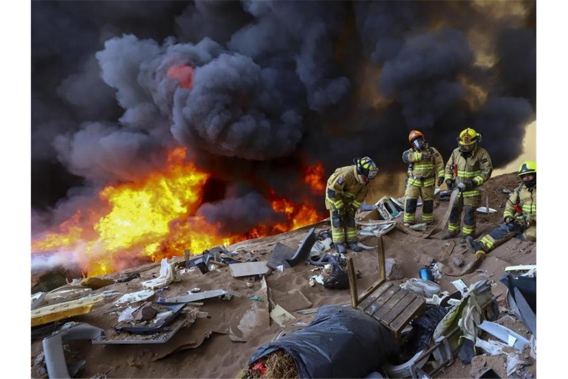 Rund 100 Häuser bei Großbrand im Norden von Chile zerstört Feuerwehrleute warten auf Wasser während eines Brandes. Foto: Ignacio Munoz/AP/dpa