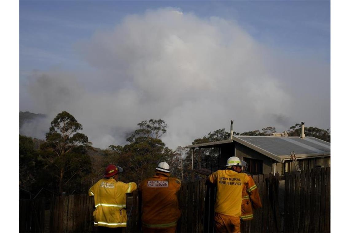 Feuerwehrmänner beobachten aufsteigende Rauchwolken eines Buschfeuers bei Penrose südlich von Sydney. Foto: Dan Himbrechts/AAP/dpa