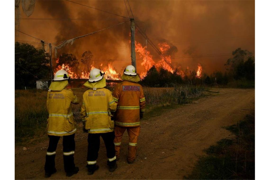 Kampf bei Rekordhitze gegen Australiens Buschfeuer Feuerwehrmänner beobachten das übergreifende Feuer auf einen Landwirtschaftsbetrieb im Bundesstaat New South Wales. Foto: Dan Himbrechts/AAP/dpa