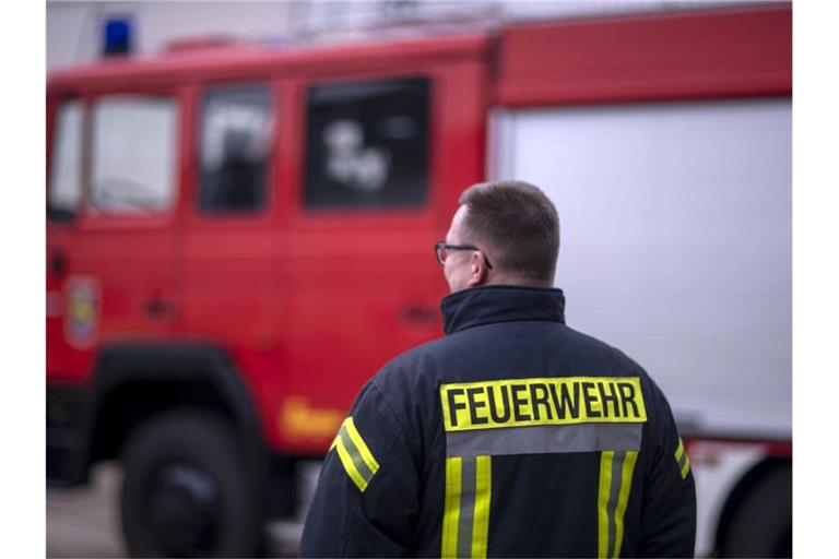 Feuerwehrmänner stehen vor einem Feuerwehrauto. Foto: Jens Büttner/zb/dpa