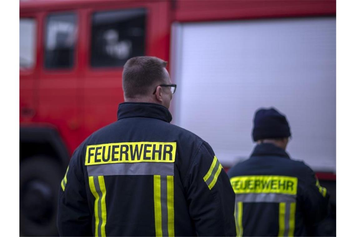 Feuerwehrmänner stehen vor einem Feuerwehrauto. Foto: Jens Büttner/zb/dpa/Symbolbild