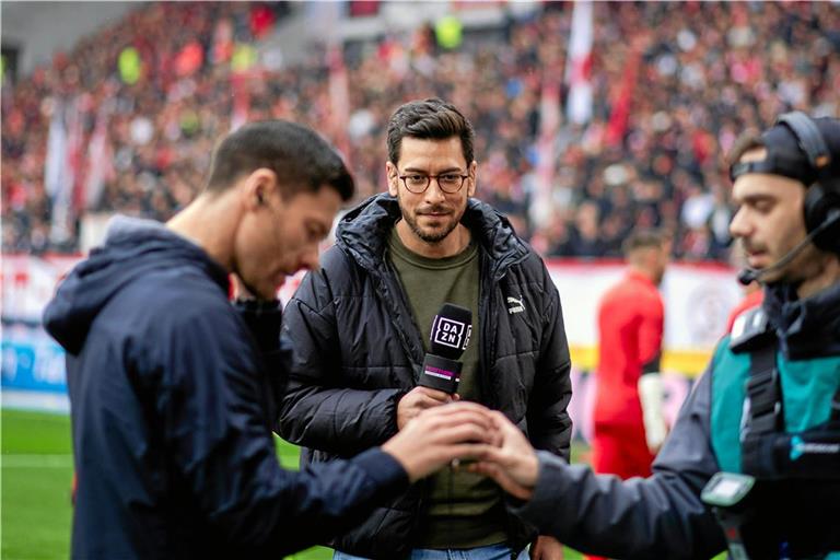 Fieldreporter Mario Rieker wartet auf das Interview, während Leverkusens Meistertrainer Xabi Alonso noch verkabelt wird. Foto: Imago