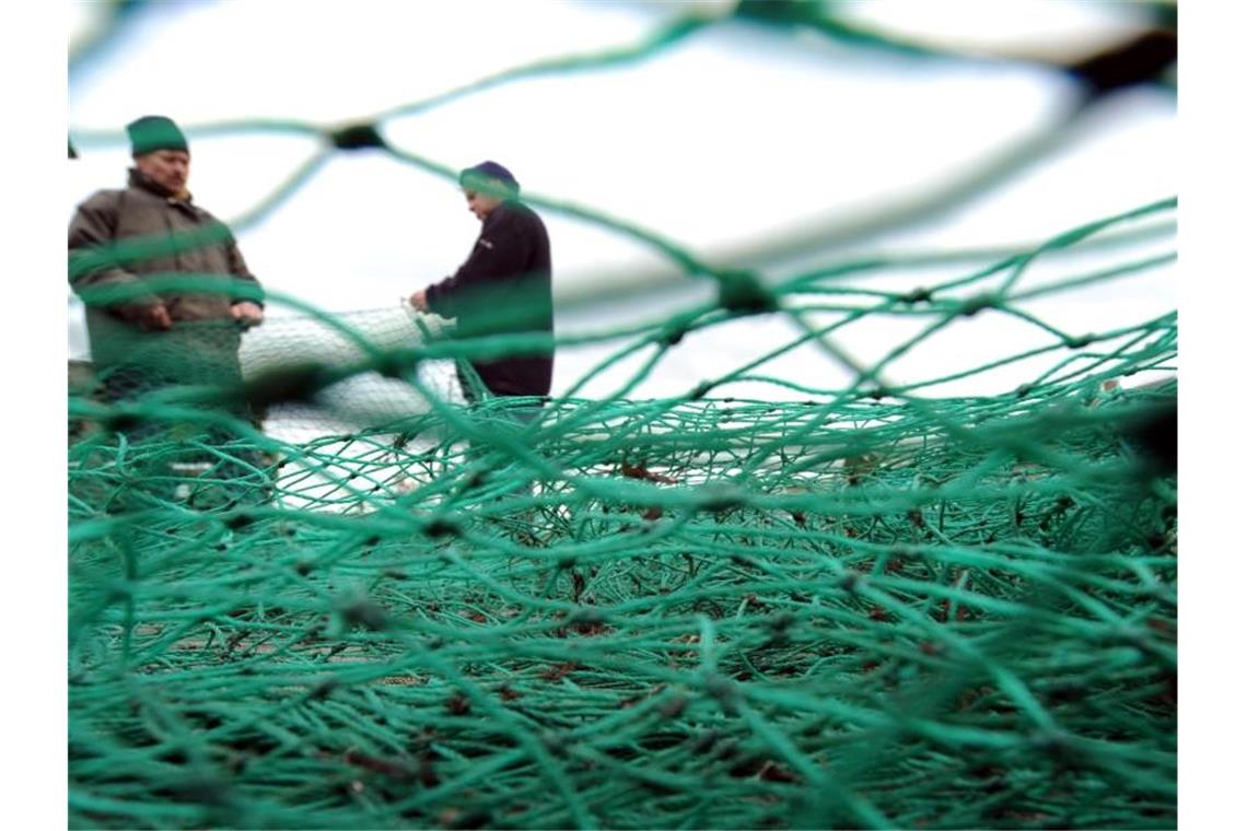 Fischer bereiten im Fischereihafen in Lübeck-Travemünde ihre Fangnetze für die nächste Fahrt vor. Foto: Marcus Brandt/dpa