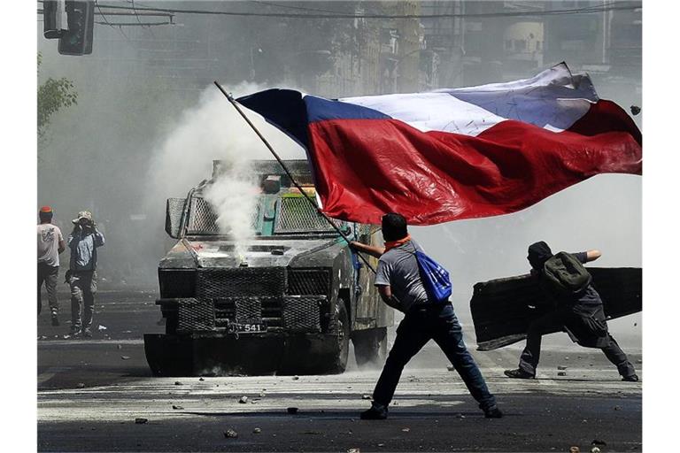 Flagge und Wasserwerfer: Momentaufnahme eines Protests in Chile gegen soziale Ungleichheit und die Regierung. Foto: Pablo Ovalle Isasmendi/Agencia Uno/dpa