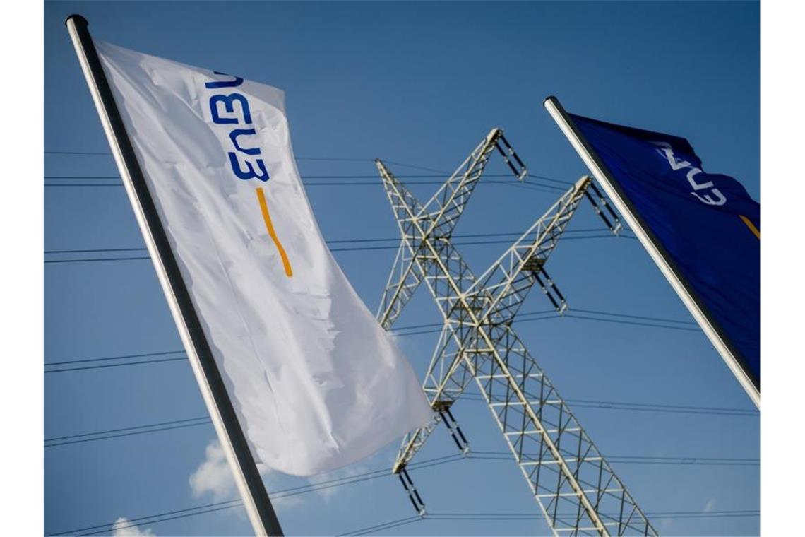 Flaggen mit dem Logo der EnBW wehen vor einem Strommasten. Foto: Christoph Schmidt/dpa/Symbolbild