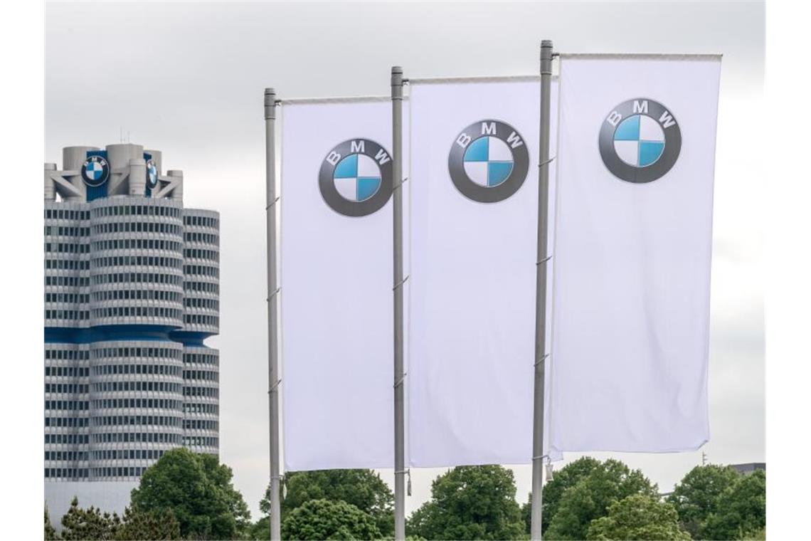 Flaggen mit dem Logo des Münchner Autobauers BMW wehen vor der Olympiahalle. Foto: Sina Schuldt/dpa