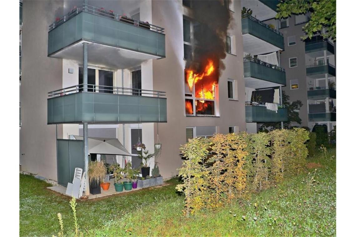 Flammen schlagen aus dem Fenster eines Mehrfamilienhauses im Stuttgarter Stadtteil Giebel. Foto: Andreas Rometsch/KS-Images.de/dpa