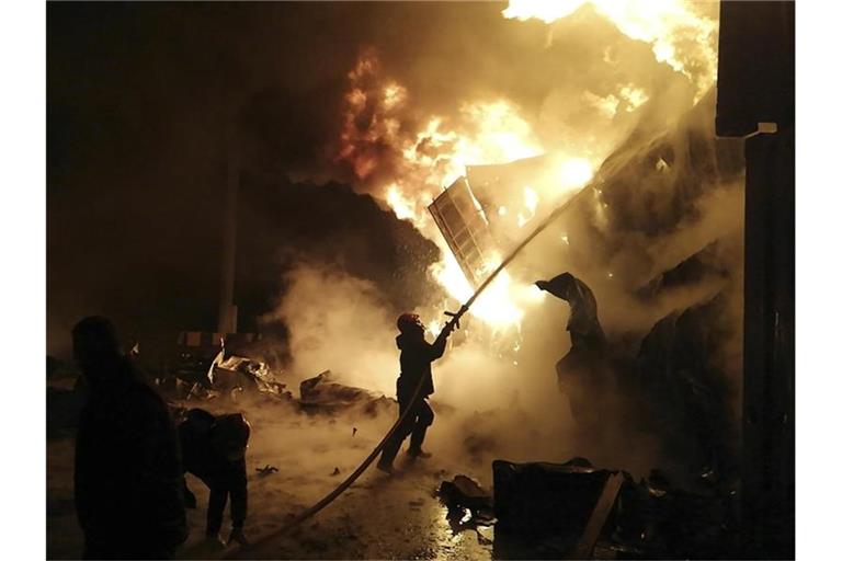 Flammen steigen aus den Containern in Latakia: Feuerwehrleute versuchen, das Feuer zu löschen. Foto: Uncredited/SANA/AP/dpa