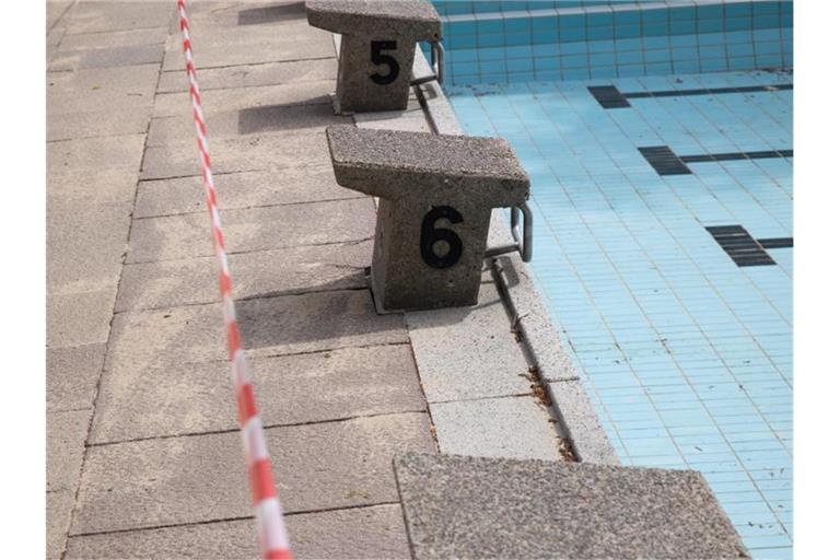 Flatterband sperrt das leere Becken in einem Schwimmbad ab. Foto: Christian Charisius/dpa/Symbolbild