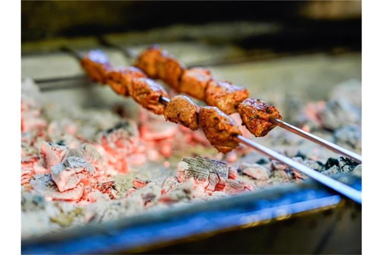 Fleischspieße werden auf einen Holzkohlegrill gelegt. Foto: Uwe Anspach/dpa/Symbolbild