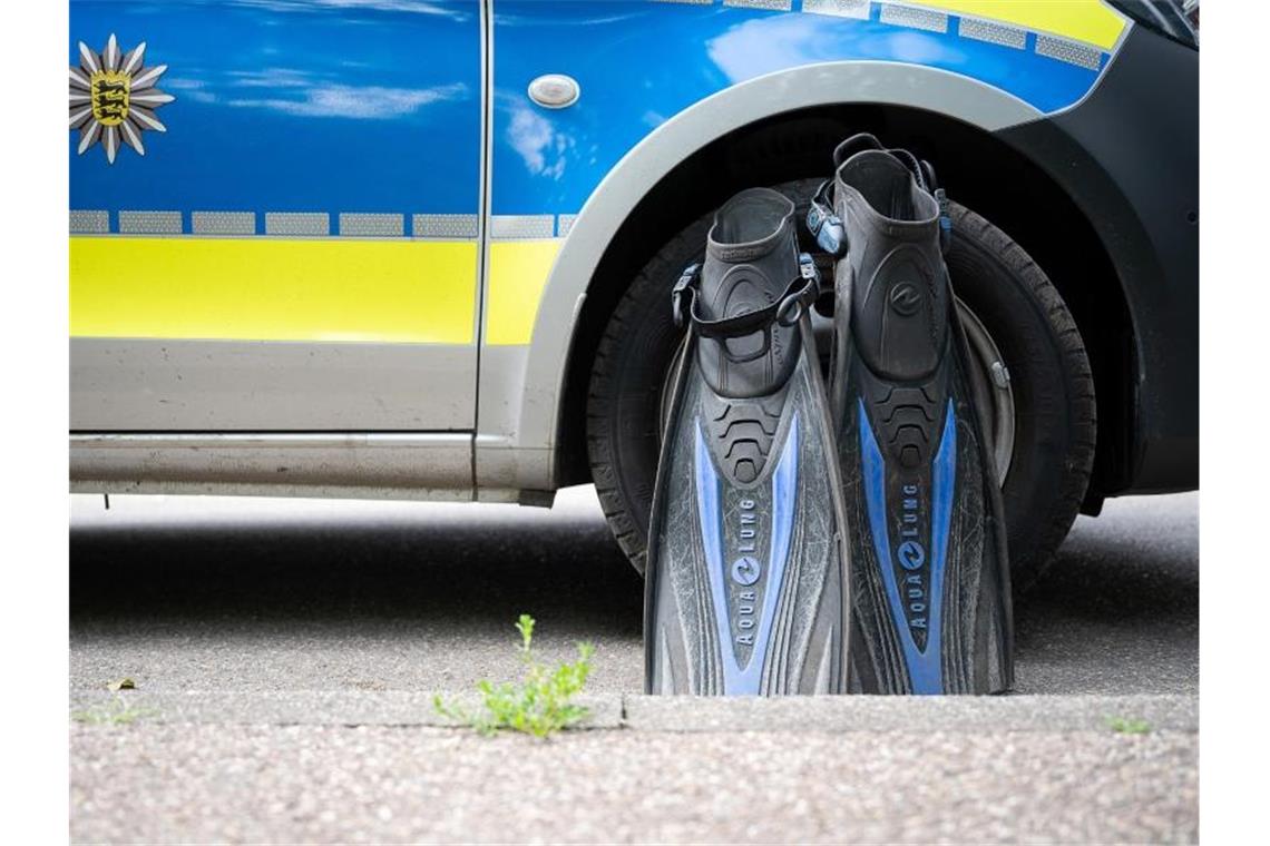 Floßen eines Polizeitauchers steht an einem Streifenwagen. Foto: Sebastian Gollnow/dpa/Symbolbild