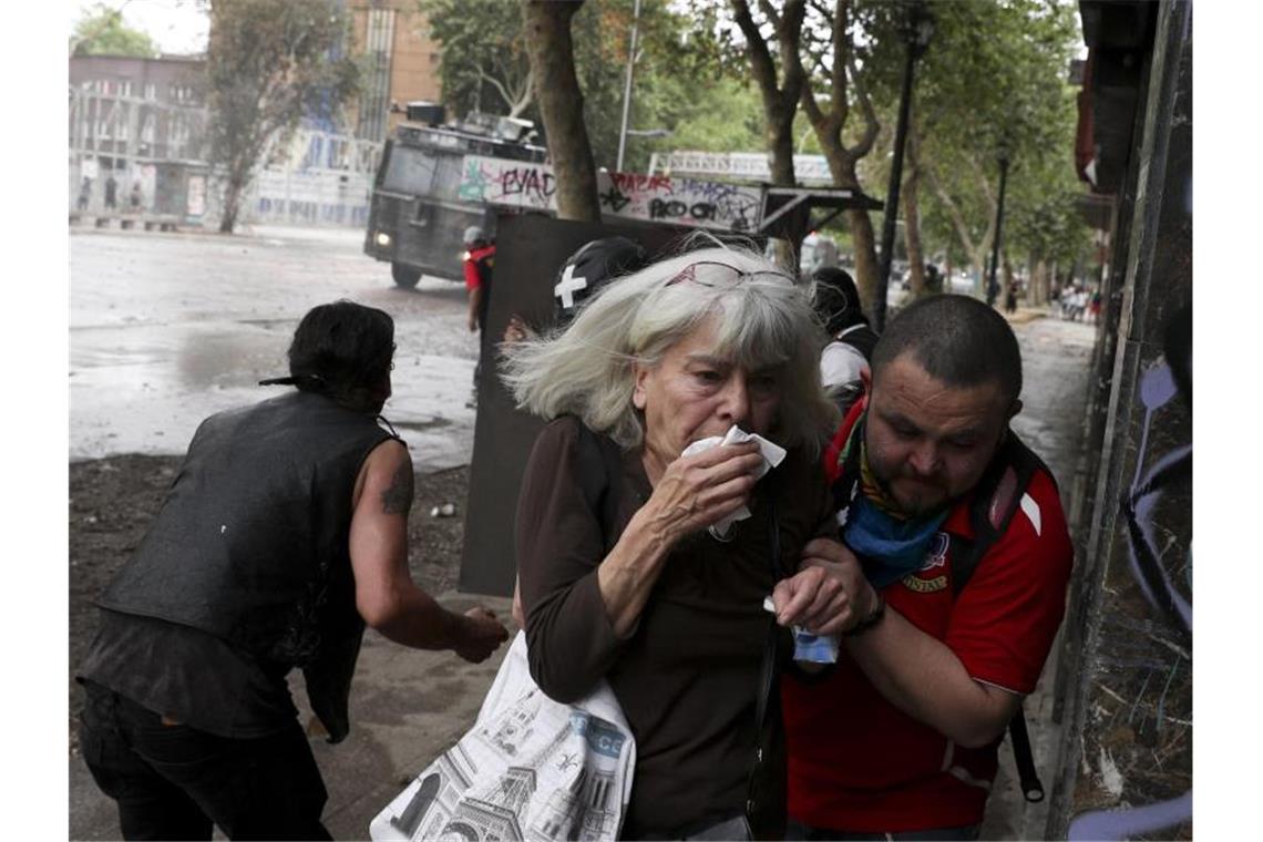75.000 Chilenen protestieren gegen soziale Ungleichheit Flucht vor dem Tränengas: Angesichts der gewalttätigen Ausschreitungen in Chile hat Präsident Piñera den Nationalen Sicherheitsrat einberufen. Foto: Esteban Felix/AP/dpa
