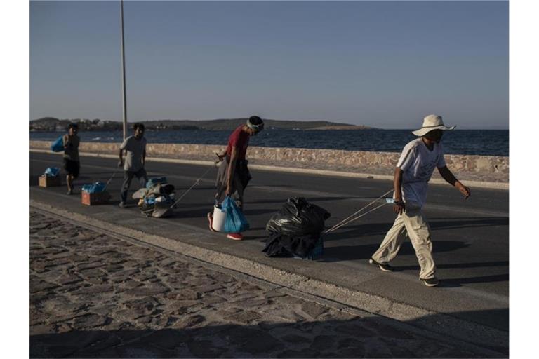 Flüchtlinge auf Lesbos ziehen ihre Habseligkeiten hinter sich her. Foto: Petros Giannakouris/AP/dpa