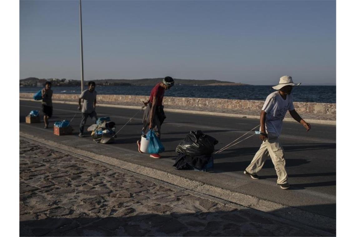 Deutschland nimmt 408 Flüchtlingsfamilien auf Flüchtlinge auf Lesbos ziehen ihre Habseligkeiten hinter sich her. Foto: Petros Giannakouris/AP/dpa
