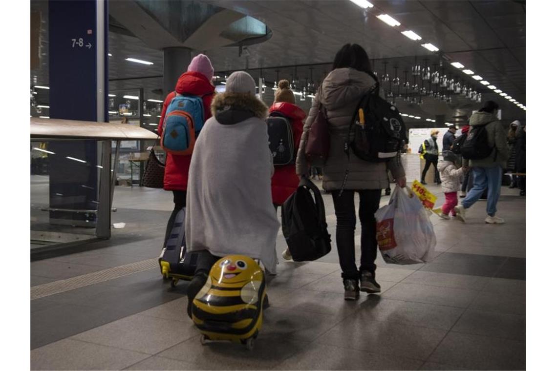 Flüchtlinge aus dem ukrainischen Kriegsgebiet gehen im Berliner Hauptbahnhof zu einer Sammelstelle. Foto: Paul Zinken/dpa