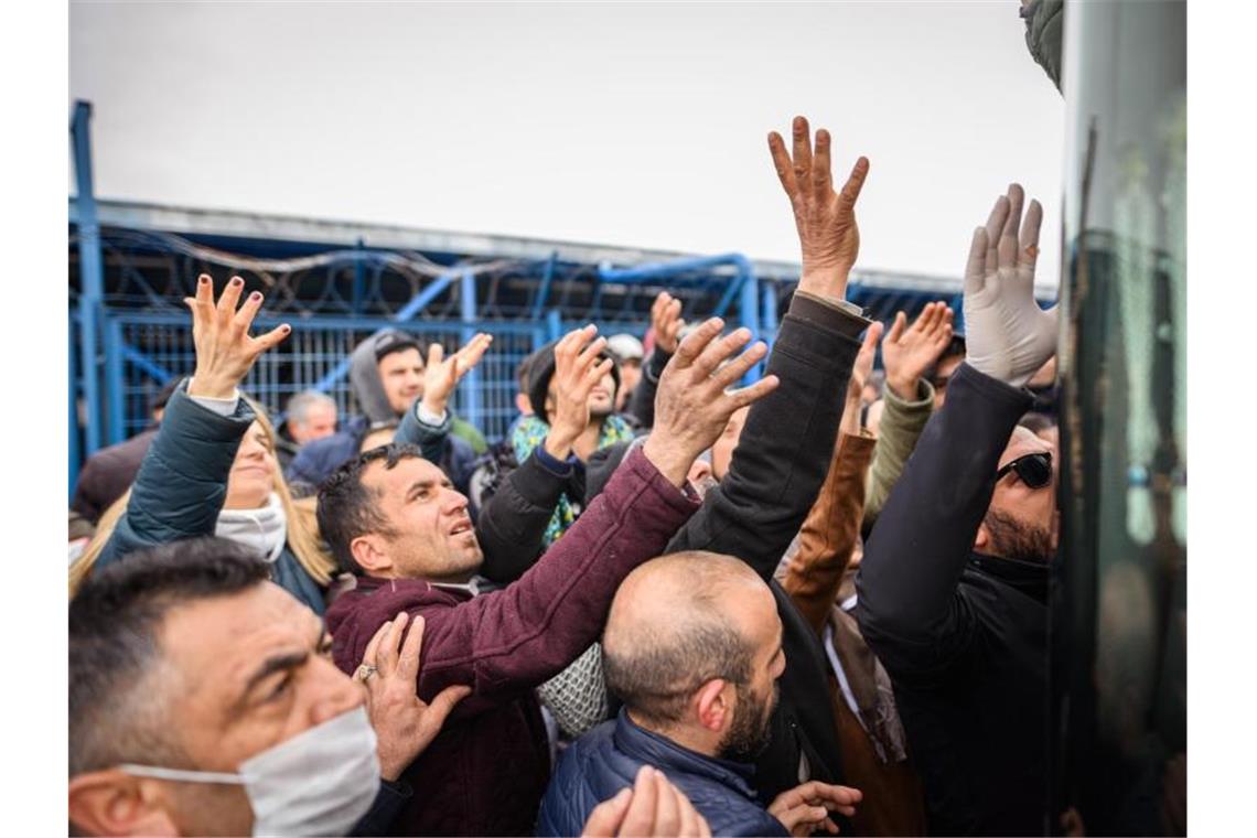 Flüchtlinge aus Syrien und anderen Ländern stehen in der türkischen Grenzstadt Edirne in der Nähe des Grenzübergangs Pazarkule-Kastanies am Bus einer Hilfsorganisation und versuchen, Hilfsgüter zu bekommen. Foto: Mohssen Assanimoghaddam/dpa