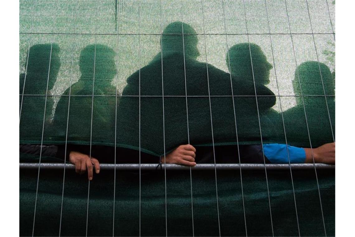 Baerbock: Flüchtlingsunterkünfte wieder aktivieren Flüchtlinge stehen im Spätsommer 2015 in einer Flüchtlingsunterkunft in Hamburg hinter einem Zaun. Foto: Daniel Bockwoldt/dpa