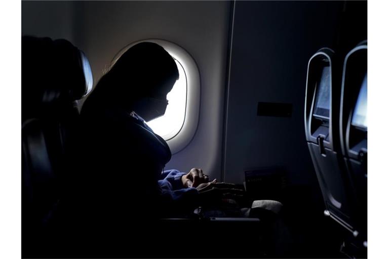 Flug-Passagierin mit Mund-Nasen-Schutz. Foto: Charlie Riedel/AP/dpa